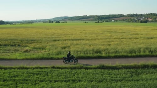 Motorcycle Riding Through Green Fields in Countryside
