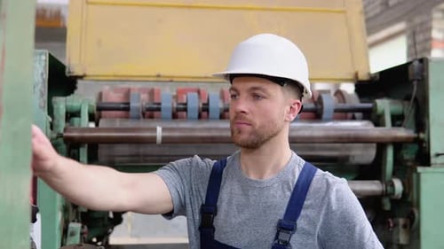 Man Operating Lever on Large Factory Machine
