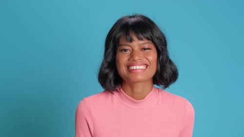 Smiling Woman Posing in Front of Blue Background
