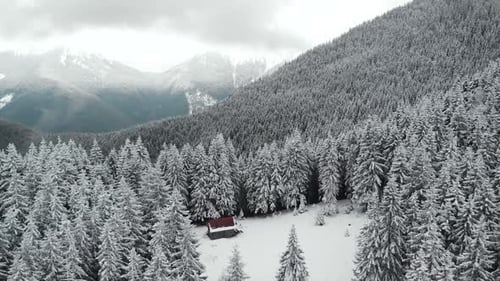 Flying Over Mountain Valley With a Log Cabin Hut