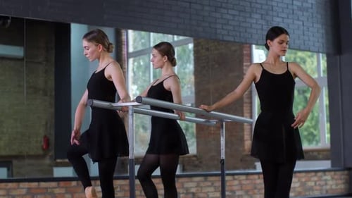 Ballet Dancers Practicing Leg Stretches at Barre