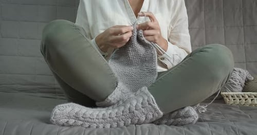 Woman Knitting Gray Wool Clothes on Couch at Home