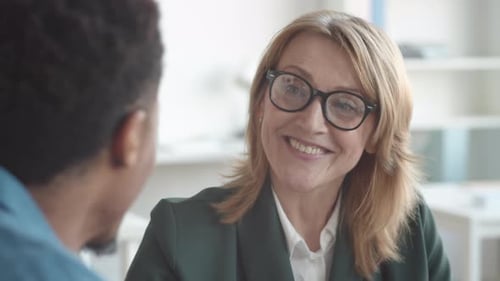 Gerente de recursos humanos sonriente hablando con un candidato negro durante la entrevista