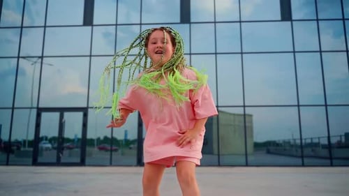 Girl dancing outdoors. Beautiful child with bright green afro hairstyle express emotions in dance