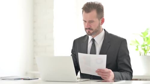 Man in Suit Reads Document and Celebrates
