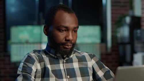 Focused Man Typing on Laptop in Office