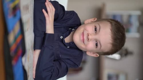 Porträt eines Vorschulkindes, der am Tisch in die Kamera schaut
