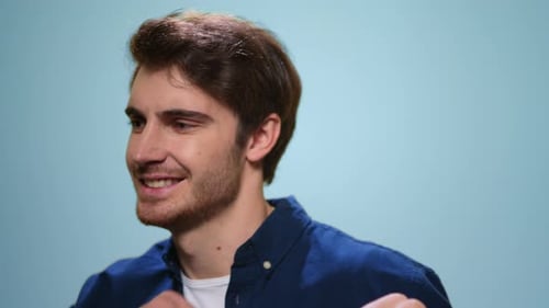 Smiling Man Dancing in Studio. Positive Guy Singing Song on Blue Background