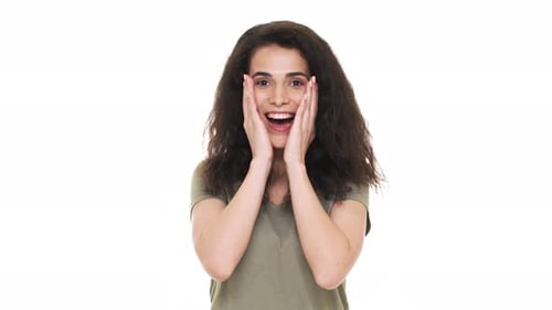 Portrait d'une femme hispanique heureuse des années 20 réagissant émotionnellement et saisissant son visage après avoir écouté