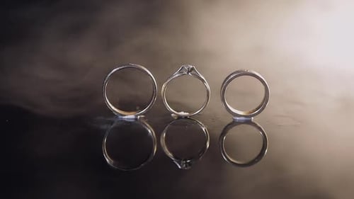 Elegant Wedding Rings on Reflective Surface with Smoke