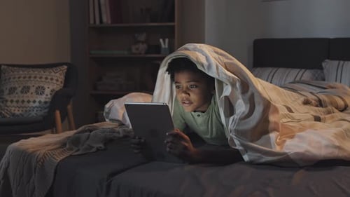Garçon utilisant la tablette dans son lit