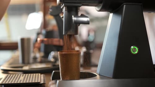 4K Asian man barista grinding roasted coffee beans in coffee grinder machine