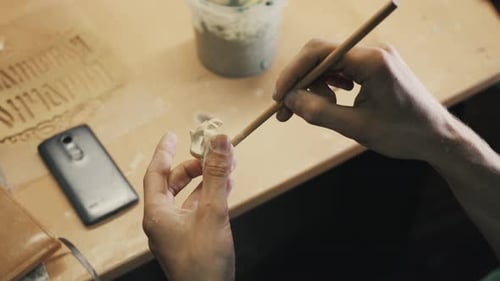 Artist Sculpting Detailed Clay Piece at Table