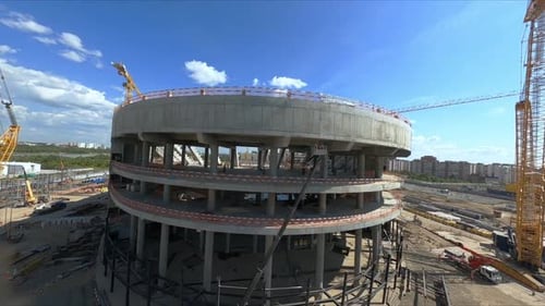 Grúas amarillas cerca del edificio de arena deportiva de concreto sin terminar