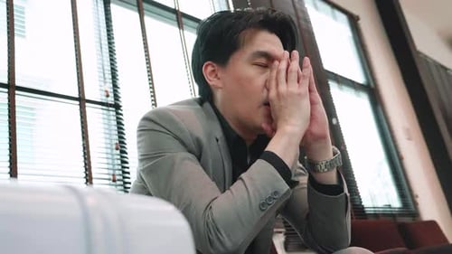 young businessman getting anxious about missed flight sitting in the departure lounge