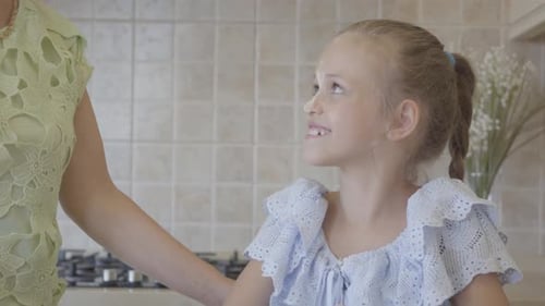Loving Moment: Woman Kisses Child in Kitchen