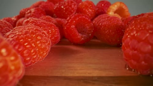 Close up slide across a bunch of fresh raspberries.