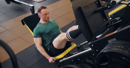 A Young Pumped Up Athlete Does Another Leg Exercise In The Gym In Preparation For Competition.