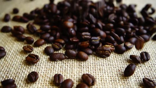 Dark Coffee Beans Poured Onto Woven Surface
