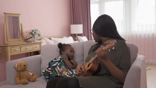 Mother and Child with Ukulele on Couch at Home