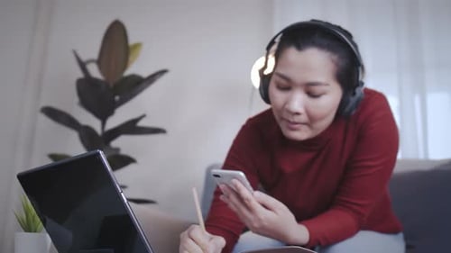 Woman Studies with Laptop, Phone, and Headphones