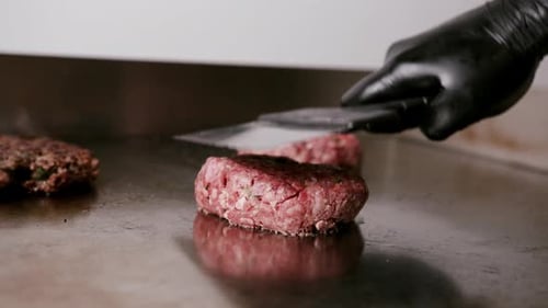 Flattening Hamburger Patties on Commercial Grill