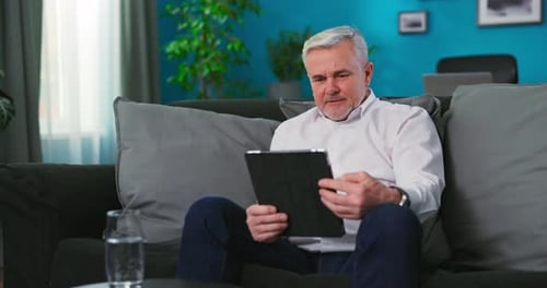 Man Relaxes at Home with Tablet Device