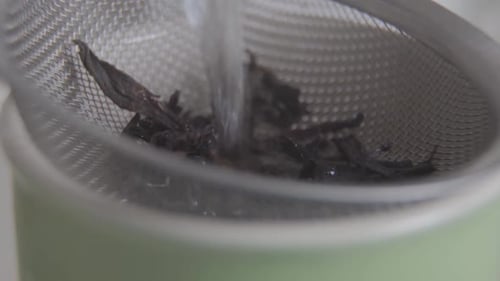 Close-up of Water Running on Tea Leaves in Cup. Hot Drink Brewing. Aromatic Morning Beverage.