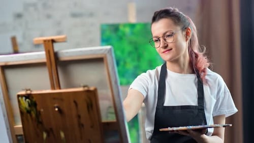 Pleasant Young Carefree Female Painter Drawing Picture at Workroom Medium Closeup