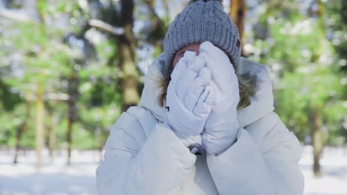 Young Woman in White Jacket and White Gloves Poses on the Camera in Winter Park