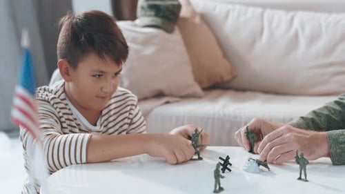 Boy and Adult Playing with Toy Soldiers at Home