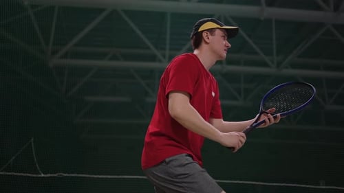 Joueur de tennis masculin actif repousse l'attaque de l'adversaire en frappant la balle par une raquette sur le court intérieur