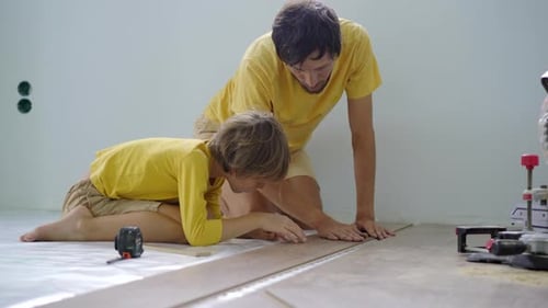 Man and Child Installing Wood Flooring Together