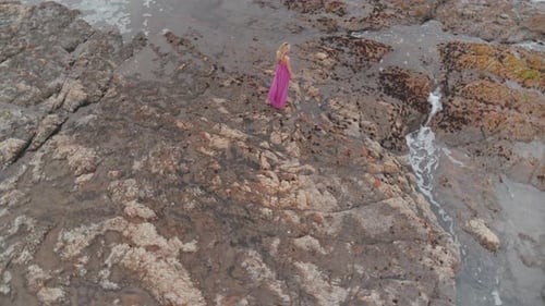 Woman Standing On The Rocky Shore