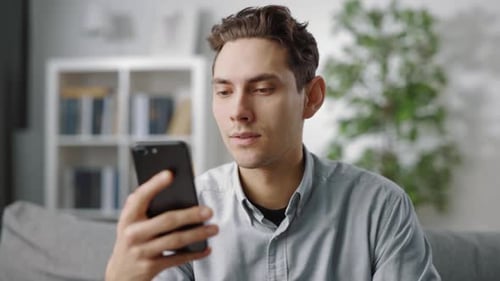 Young Man Using Smartphone at Home Indoors