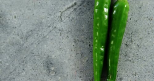 Two green chilli pepper on concrete