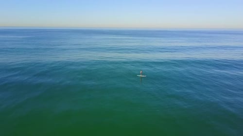Aerial drone uav view of a SUP stand-up paddleboarder surfing.