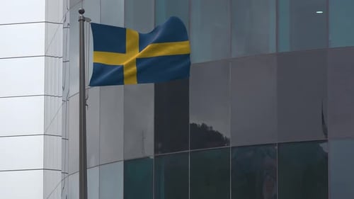 Swedish Flag Waving in Wind on Modern Office Building