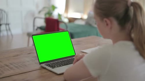 Vista trasera de una hermosa mujer trabajando en una computadora portátil con pantalla verde cromática