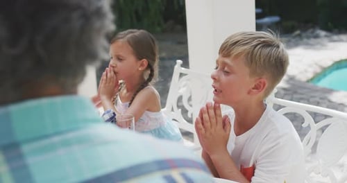 Children Praying Together with Family Member Outdoors