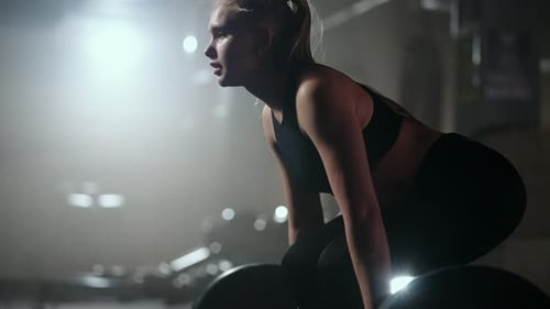 Female Bodybuilder Doing Exercise with Weights in Gym