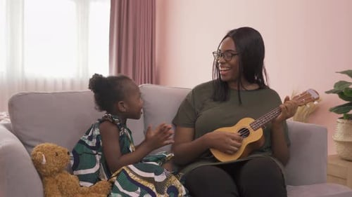 Mom Playing Ukulele with Child on Couch