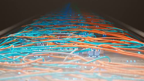 Countless colourful cables in a vintage server room cabinet lit by a spotlight.