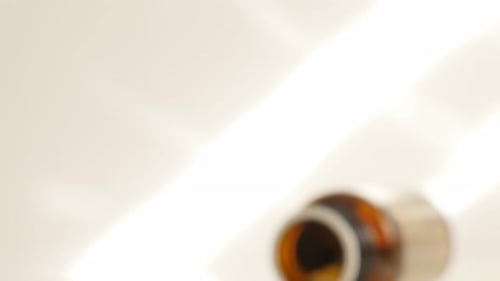 Pills spilling from bottle on white surface