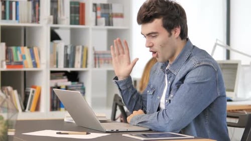 Man Working at Laptop in Office Talking