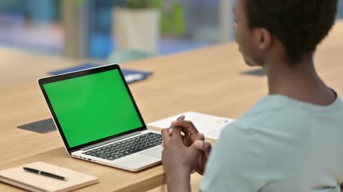 Adult Communicating at Table Using Chroma Key Laptop