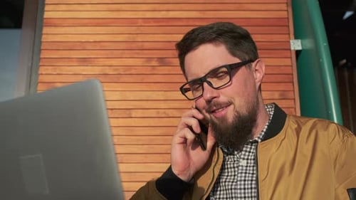 Bearded Man Talking on Phone with Laptop