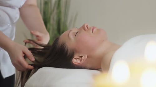Pretty Brunette Woman Gets a Head Massage in the Bright Office of the Spa Salon
