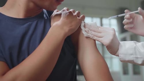 Close Up Medical Nurse In Safety Gloves Is Making A Vaccine Injection To A Male Patient