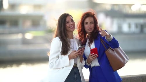 Two Women Walking Around the City Together, Standing Against the Background of the River. Women's